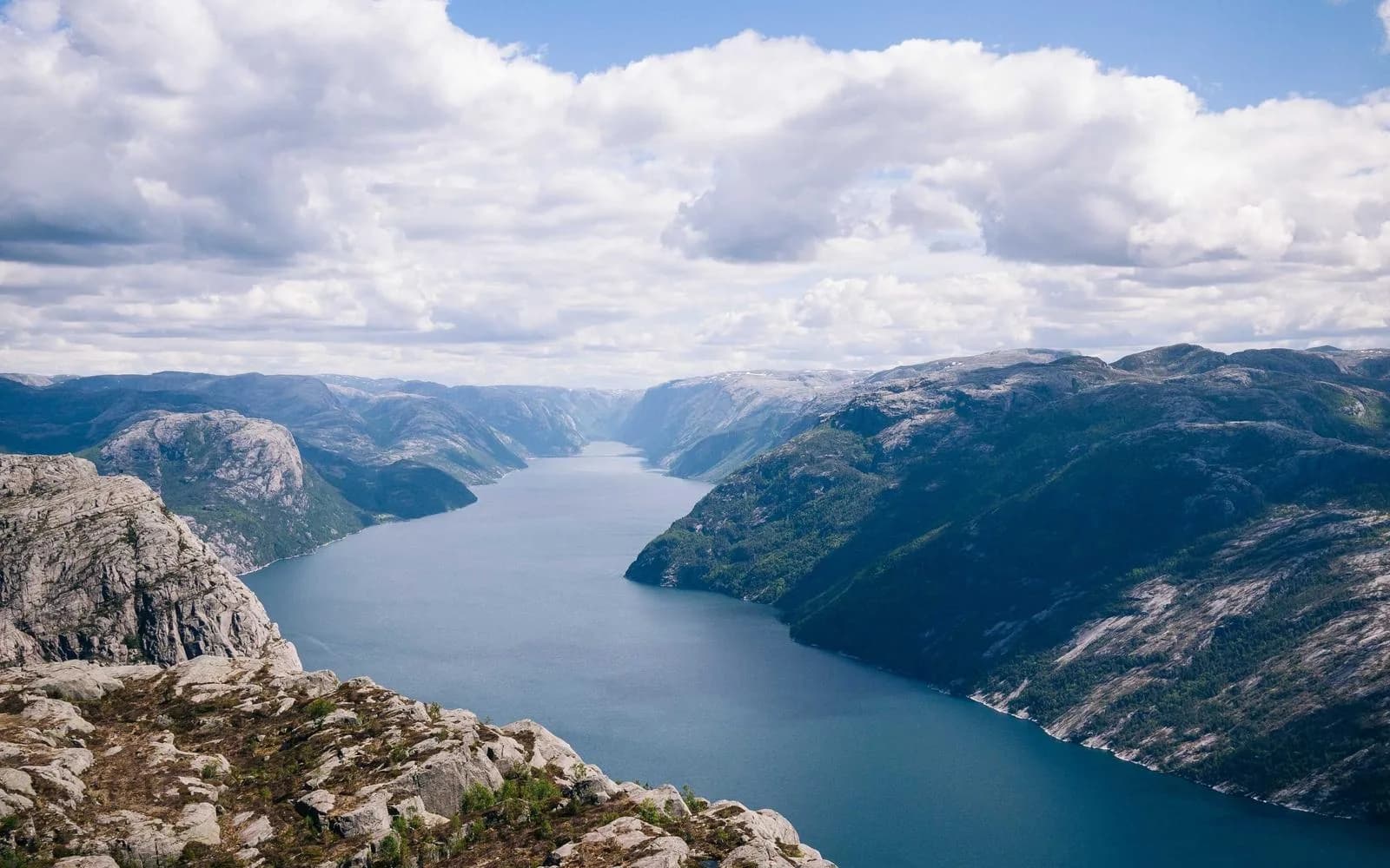 An aerial view of a narrow fjord winding between steep mountains