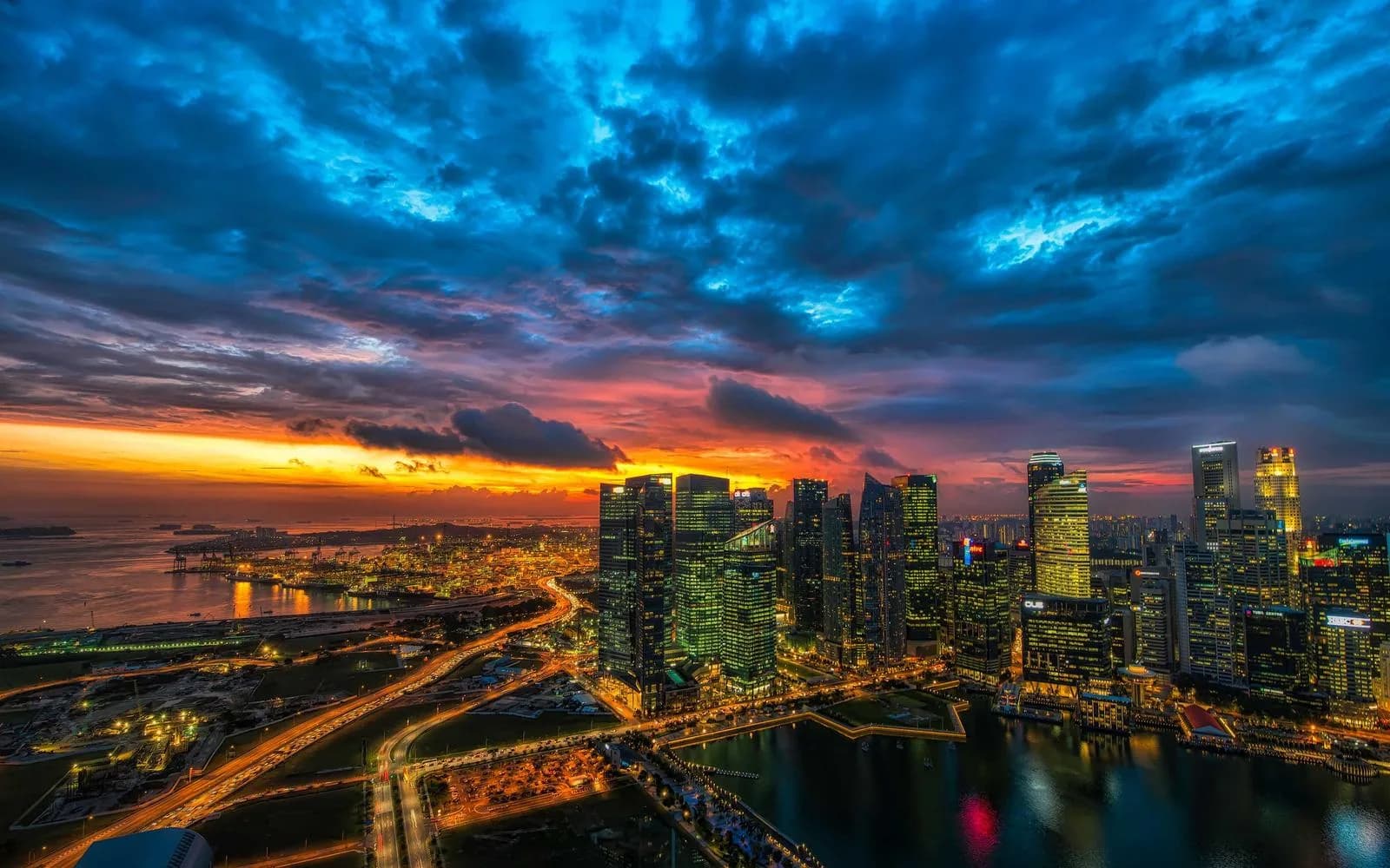 A city skyline lit up at dusk beneath dramatic storm clouds